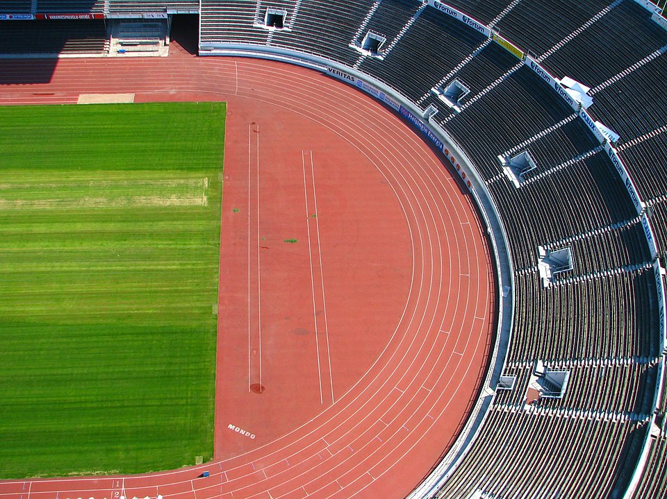 An elevated view of an oval running track, useful for comparing the distance around one lap with the zero displacement of a runner who finishes at the starting point.