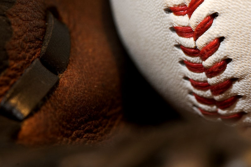 A close view of a baseball resting beside the pocket of a brown baseball glove.